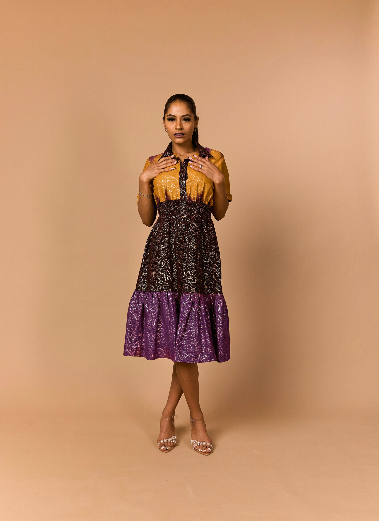 Woman wearing a two-tone dress with a mustard top and purple skirt on a beige background