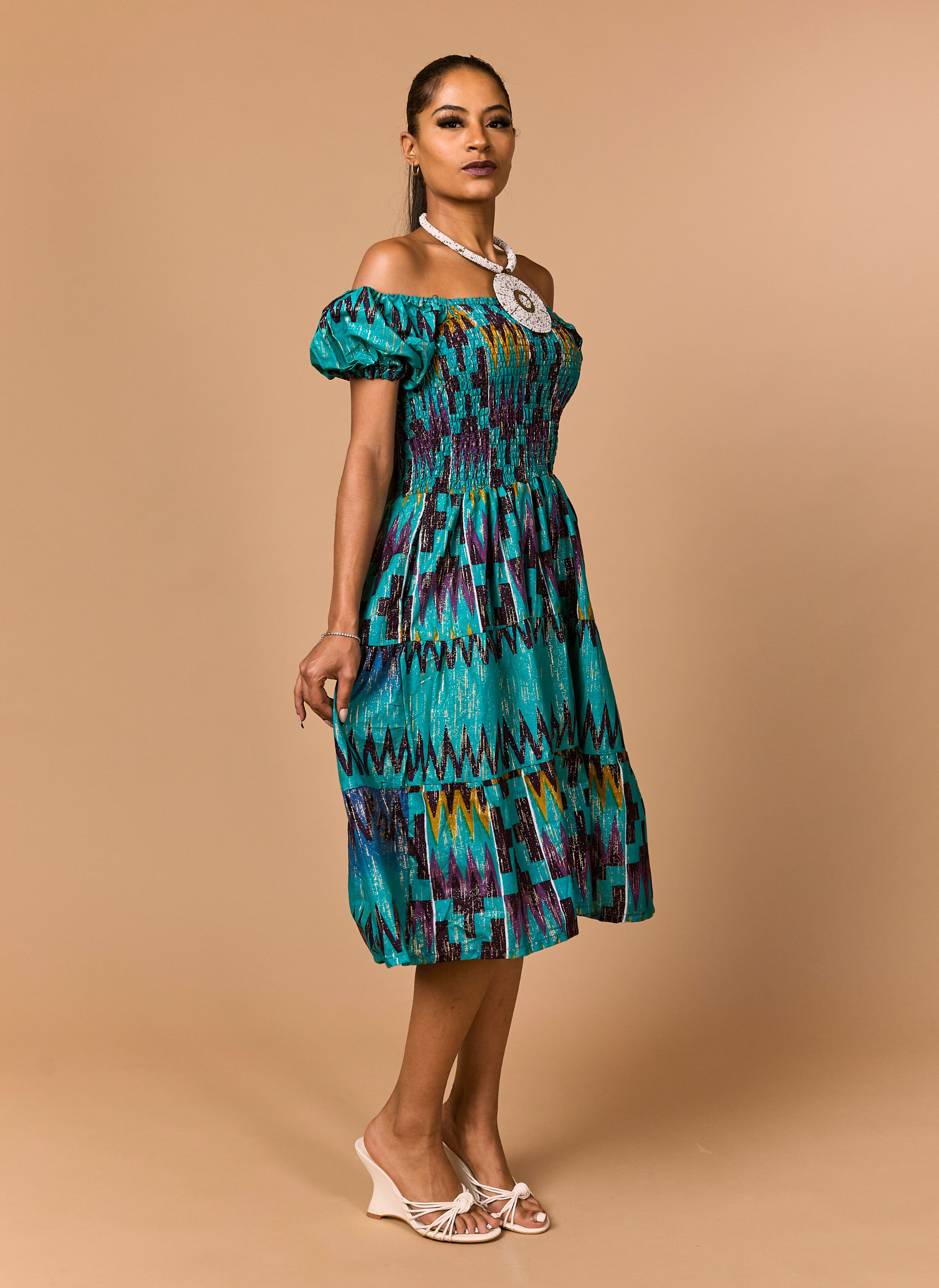 Woman wearing a colorful patterned dress on a beige background