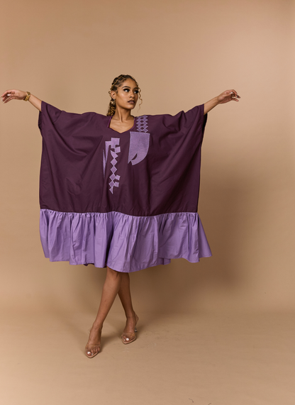 Woman wearing a purple dress with a geometric pattern on a beige background